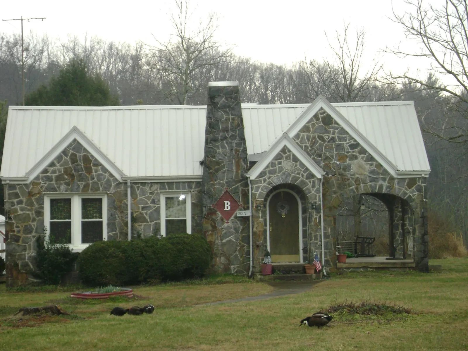 White metal roof on a stone cottage with steep gables in Monroe